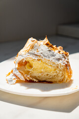A flaky pastry slice shows layers of rich cream, glowing in golden light