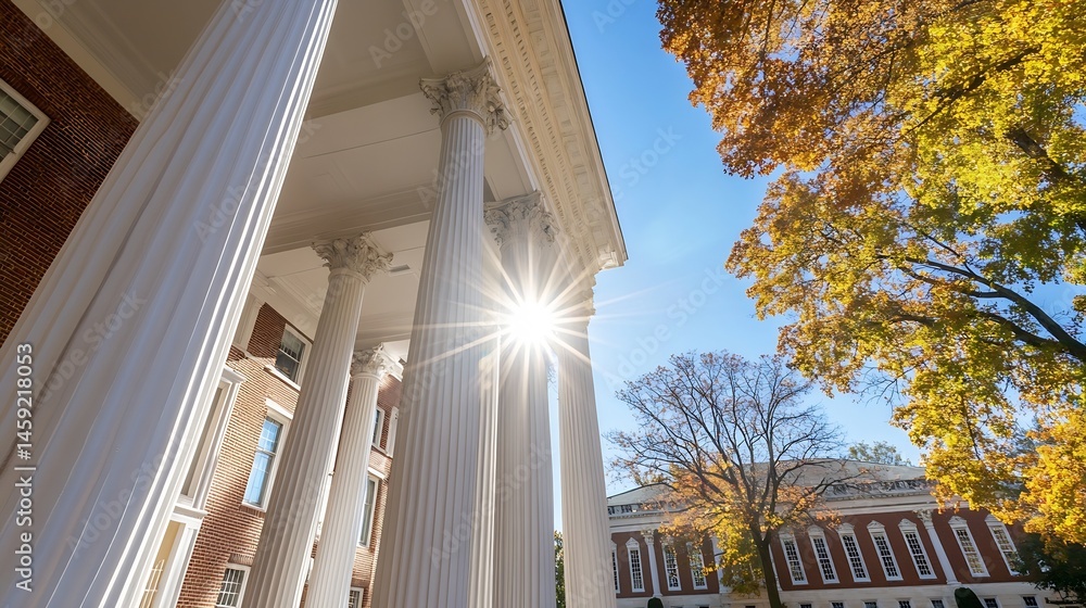 Poster sunbeams illuminate classical columns of a brick building, autumn leaves frame the scene under a bri