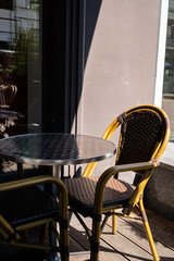 A charming café corner features a metal table and two woven chairs catching the sun’s rays
