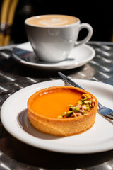 Savoring a tasty orange custard tart with nuts and a warm drink