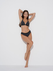 Woman in swimwear poses confidently in a studio setting highlighting fashion