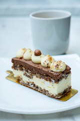 A rich slice of cake with cream and hazelnuts pairs perfectly with a warm drink