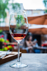 Rose wine sparkles in the sun as patrons socialize at an outdoor cafe on a warm day