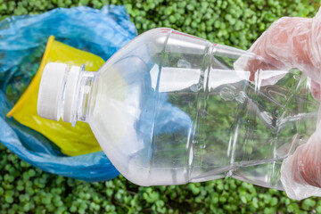 Hand in glove holding a plastic bottle for disposal
