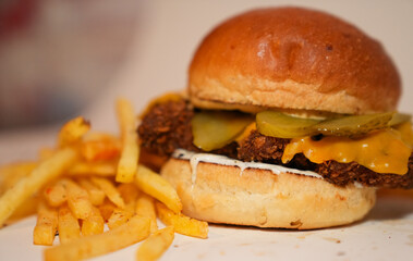 Close up view of french fries and hamburger with meat, pickled gherkins slices, and cheese isolated on white background.