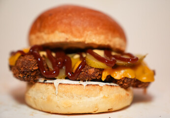 Close up view of hamburger with meat, pickled gherkins slices, barbecue sauce, and cheese isolated on white background.