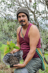 Rural farmer holding a small tree ready for planting, symbolizing sustainability, reforestation,...