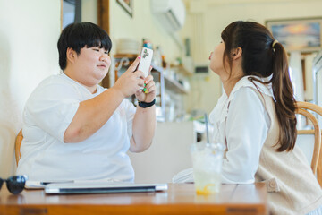 Asian couple lgbtq lifestyle activity enjoying time together using smartphone in cozy cafe