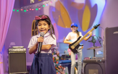 Young girl with a bright smile passionately sings into a microphone on a brightly lit stage