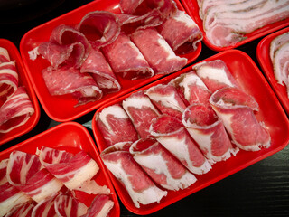 Sliced Meat and belly pork in tray for shabu or Sichuan mala hotpot on restaurant table.