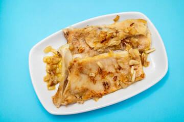 Fried cod ffish with onion and pepper on dish