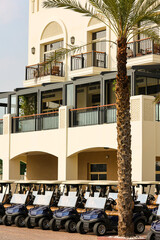 Luxury Golf Resort with Line of Golf Carts and Palm Trees Elegant golf resort exterior featuring a row of modern golf carts parked