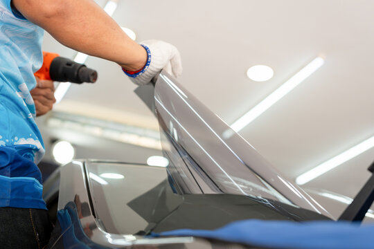 Worker man tinting car window with heat gun in workshop, Male specialist applying car tinting film - Powered by Adobe