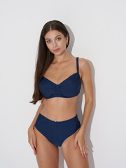 Fototapeta premium tanned sexy slim woman in blue bikini against white wall