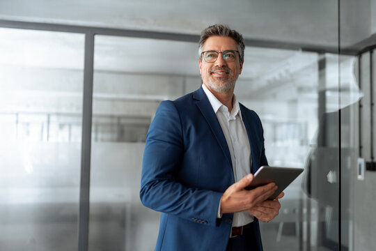 Smiling senior businessman entrepreneur working on touchscreen computer device. Dreaming mature 50s Latin ceo business man ceo manager using tablet pad computer in office, looking at copy space  - Powered by Adobe