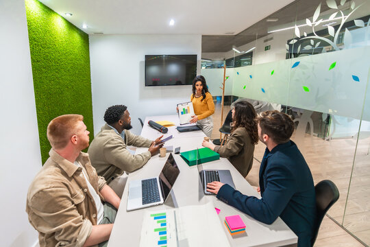 Marketing team analyzing charts during business meeting in modern office - Powered by Adobe