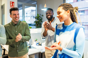 Happy business team applauding a female colleague in modern office