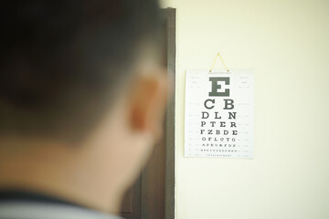 Man during an eye exam looking at a Snellen chart