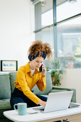 Portrait of a woman using laptop and tablet while sitting on a Green couch at home office