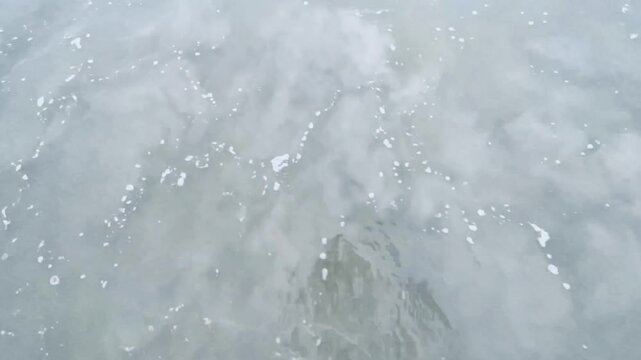 Sea waves approach the shoreline in slow motion move. Wave breaking on sea shore in a quiet and calm of misty morning atmosphere.	