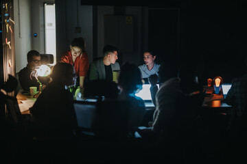 A group of colleagues work together on a project in a dimly lit office atmosphere, providing a...