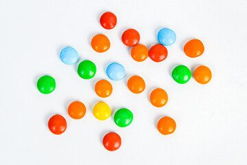Small colorful candies scattered. Colorful coated chocolates, various candy collections, rainbow candies on a white background. Perfect for concepts like sweetness, fun, or celebration.