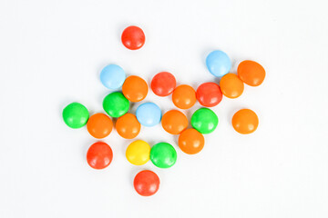 Small colorful candies scattered. Colorful coated chocolates, various candy collections, rainbow candies on a white background. Perfect for concepts like sweetness, fun, or celebration.