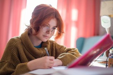 schoolgirl with glasses doing homework.