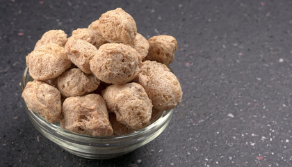 Raw soya chunks on dark background. Healthy, nutritious soybean meat, chunks isolated.Vegan food concept.