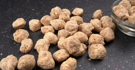 Raw soya chunks on dark background. Healthy, nutritious soybean meat, chunks isolated.Vegan food concept.