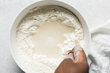 Overhead view of steamed bun dough being mixed in a bowl, top view of mantou dough being mixed, process of making steamed buns
