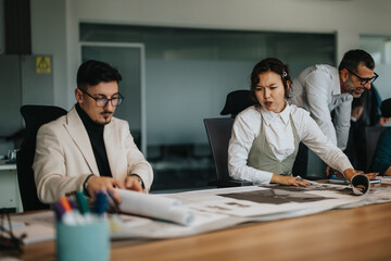 Fototapeta premium A group of business professionals engage in a collaborative discussion, analyzing and strategizing on projects at a modern office environment.