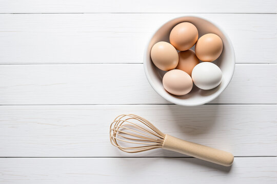 six brown eggs and one white egg in a bowl with a wooden whisk