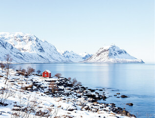 red house on snowy shore with mountain and sea view