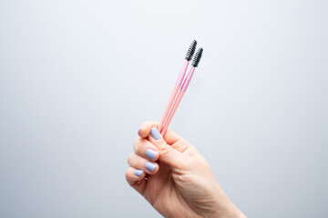Woman holding pink eyebrow brush close-up. Eyebrow artist paints eyebrows with dye