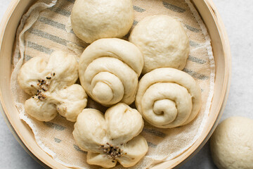 Overhead view of steamed bun in a steamer basket, top view of mantou in a bamboo steamer, process of making steamed milk buns