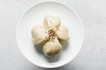 Overhead view of steamed bun on a white plate, top view of mantou on a white background, process of making steamed milk buns