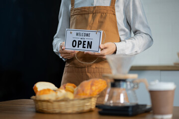 Owner of the cafe stands at the door with a sign Open waiting for customers. Small business concept, cafes and restaurants.