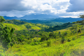 Lush green hills and distant mountains under cloudy sky