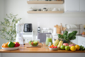 Fresh fruits, vegetables, and a blender on a wooden kitchen counter for healthy meal preparation.