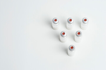 Flatlay of vaccine vial bottles with copy text space on white background. Flatlay of vaccine vials...