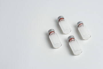 Flatlay of vaccine vial bottles with copy text space on white background. Flatlay of vaccine vials...
