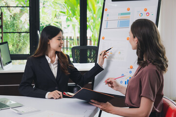 Businesswoman making a presentation at work in front of colleague. Businesswoman coach mentor explain graph chart on flipchart corporate group workshop training in meeting room.