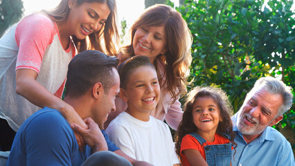 Multi-Generation Hispanic Family Relaxing In Garden At Home Together