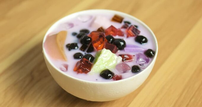 Rotating bubble tea revealing layered ingredients, vibrant jellies, black tapioca pearls, smooth pudding swirling within creamy beverage