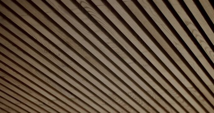 Wooden planks on a ceiling, creating an interesting perspective. The parallel lines and warm tones of the wood add a touch of modern design. Ideal for backgrounds, architecture, or design projects.