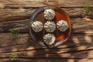 Freshly made uncooked handmade khinkali, the traditional Georgian dumplings, in bright sunlight, showcasing fresh ingredients and the art of cooking in action.