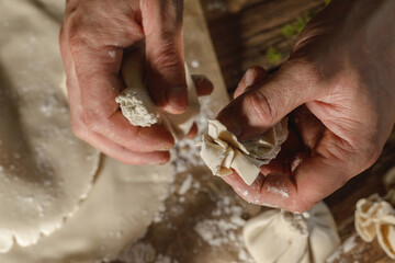 Hands expertly mold khinkali, the traditional Georgian dumplings, in bright sunlight, showcasing fresh ingredients and the art of cooking in action.