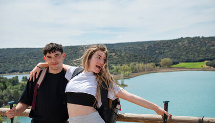 Happy young couple hiking and embracing by a scenic mountain lake