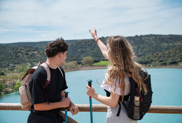 Young hikers pointing and enjoying lake view from wooden railing